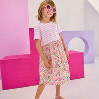 Model can be seen wearing a half knit half woven dress with knit pink/white stripe top half and a woven skirt with pink/yellow floral print. There is also a three button closure along back for a relaxed but secure fit.