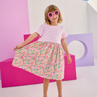 Model can be seen wearing a half knit half woven dress with knit pink/white stripe top half and a woven skirt with pink/yellow floral print. There is also a three button closure along back for a relaxed but secure fit.
