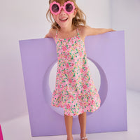 Model can be seen in woven dress with thin straps in a hot pink/yellow/white floral pattern. Dress is made up of a lightweight woven material for a perfect spring/summer dress.