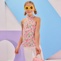 Girls/Tween woven scarf top in a beautiful hot pink floral pattern. Top features two button closure on back neckline and has a criss cross detail with the straps to create the scarf top affect. Model can be seen pairing this top back with our ivory denim jeans to complete the look.