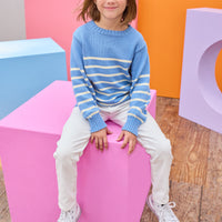 Tween model can be seen wearing blue and white stripe sweater paired back with ivory jeans to complete the look .