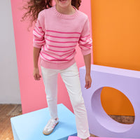 Tween model seen wearing a striped light pink and hot pink sweater paired back with ivory jeans for a comfy yet elevated look.