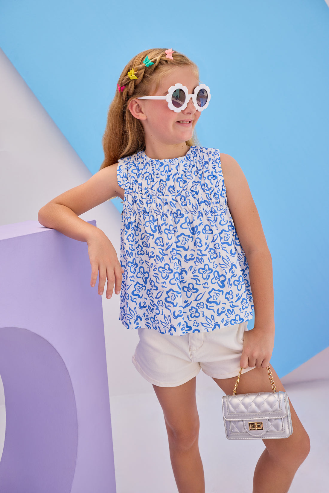 Model can be seen wearing Girls/Tween sleeveless woven top in a blue and white floral print. Top features ruching at the bust and fans out for a relaxed comfy fit. Pair back perfectly with ivory denim shorts to complete the look.