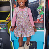 Little girl seen wearing our Essential Tee in Blush Stripe layered underneath our Beatrice Pinafore dress in Radnor Rose--BISBY girl