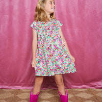 Girls short sleeve dress in magenta/pink/orange/green floral print with light pink trim detail and button closures along back.