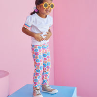 Toddler girl wearing colorful BISBY leggings in flower market pattern with pink, blue, and orange flowers.