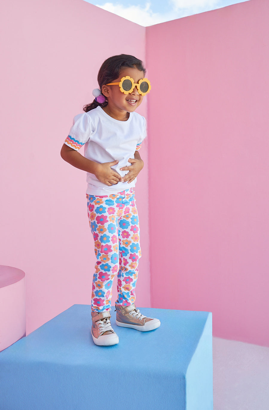 Toddler girl wearing colorful BISBY leggings in flower market pattern with pink, blue, and orange flowers.