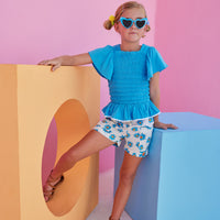 BISBY girl wearing our new Patch Pocket Shorts in our Fenwick Blue floral pattern. These shorts have pockets in the front and fixed ties with an elastic waistband. They pair perfectly back with our India Top in Blue or even our Michaela top in Fenwick Blue for a completed look.