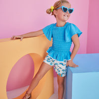 BISBY girl wearing our new Patch Pocket Shorts in our Fenwick Blue floral pattern. These shorts have pockets in the front and fixed ties with an elastic waistband. They pair perfectly back with our India Top in Blue or even our Michaela top in Fenwick Blue for a completed look.