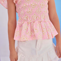 Model can be seen wearing Girls/Tween woven top that has a ruching feature across middle of top. Top is made of yellow and white flowers printed on a light pink background and also features angel sleeves for an elevated look. Pair back perfectly with our ivory denim skirt to complete the look.