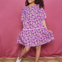 Girls/Tween woven dress which features a slight v-neck neckline, elbow length sleeves, and a pic rack detail along the bottom tier of dress. Print is made up of a magenta/pink/purple floral arrangement.