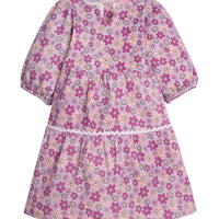 Girls/Tween woven slightly v-neck dress in our Petal floral which features an arrangement of magenta/purple/pink flowers on a light purple background. Dress has a ric rac detail along bottom tier and elastic cuffs on the sleeves. Dress also has button enclosures along the back-BISBY