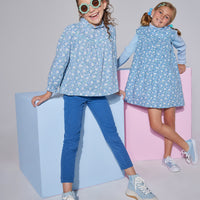 Model on left can be seen wearing corduroy pants in a deep blue color. Pants are made of a soft corduroy material and feature a button/snap closure at zipper for easy put on access. Pants can be seen paired back with a long sleeve woven top in a blue floral pattern to complete the look.Model on right can be seen wearing a dress in the matching blue floral pattern with an ice blue ribbed turtleneck underneath to complete the matching looks.