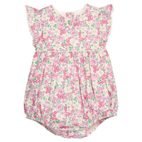 BISBY baby knit bubble in a pink/green floral print. Bubble features button closure along back and stride, white pom pom detail across the middle/bust area, and white pom pom detail along sleeve cuffs for an elevated look.