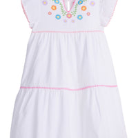 Girls/Tween woven white tiered dress with multi-color floral embroidery detail on chest/along the v-neck neckline. Dress also features light pink pom poms along sleeve and first and bottom tiers of dress. A row of bubblegum pink pom poms is seen along the second tier of dress and around neckline. There is also a button closure at back of neckline for a secure fit