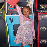 Girl seen wearing our Beatrice Pinafore - Radnor Rose Dress layered with our essential long sleeve tee (White and Pink Stripe)--BISBY girls