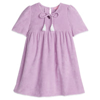 Girls/Tween lilac terry cloth dress that features a slight v-neckline, light pink pom pom detail at sleeves, and tie tassels at top of neckline. There is also a button closure at back for a relaxed but secure fit.