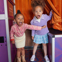Little girl can be seen wearing our Lilac Polo pullover layered with our Cream colored essential turtleneck underneath paired with our skirt in Seville Azul. Little girl on left can be seen wearing our Seville Rose turtleneck paired with our Mini Sherpa skirt--BISBY girl