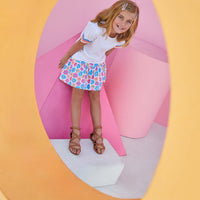 Smiling girl wearing vibrant sally skort featuring blue, pink, and orange flowers.