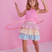 BISBY girl in our Tiered Mini Skort in our "Daisy Chain" with top tier in pink, middle tier in orange, and bottom tier in blue floral pattern. Skort has built in shorts and has elastic waistband. Paired perfectly with our Hot pink halter top