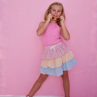 BISBY girl in our Tiered Mini Skort in our "Daisy Chain" with top tier in pink, middle tier in orange, and bottom tier in blue floral pattern. Skort has built in shorts and has elastic waistband. Paired perfectly with our Hot pink halter top