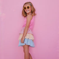 BISBY girl in our Tiered Mini Skort in our "Daisy Chain" with top tier in pink, middle tier in orange, and bottom tier in blue floral pattern. Skort has built in shorts and has elastic waistband. Paired perfectly with our Hot pink halter top