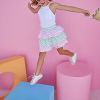 BISBY girl in our Tiered Mini Skort in Pink & Green Stripe which features pink and green tiers with a fixed tie and elastic waistband. These shorts are also perfect for your active girl because they have built in shorts as well. Pair it back with our halter top in white for a fun elevated look.