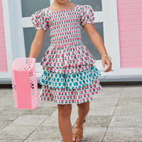 Little girl smiling and wearing our tiered skort with pink and blue flowers alternating colors on each tier.