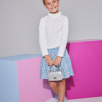 Girls/Tween knit top in white features a few button closures along the back and a ruffled neckline to add to the look. Model can be seen wearing top with our skort in a blue floral arrangement to finish off the look.