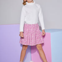 Girls/Tween knit top in white features a few button closures along the back and a ruffled neckline to add to the look. Model can be seen wearing top with our skort in a fuchsia floral arrangement to finish off the look.