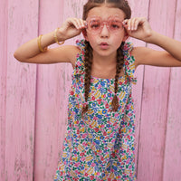 Little girl wearing ruffle adjustable strap sundress which features a square neckline and a colorful floral print.