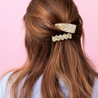 Long brown hair with decorative hair clips on a pink background