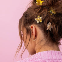 Person with hair styled with star hair clips against a pink background