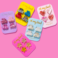 Set of colorful hair clips in packaging on a pink background