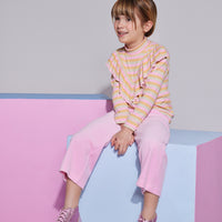Girl/Tween cropped velour pants in the light pink velour shade. Pants feature a soft velour material, with pockets in the front, and an elastic waistband for a comfy fit. Model can be seen wearing a knit top with angel sleeves in a pastel stripe pattern to complete the look.