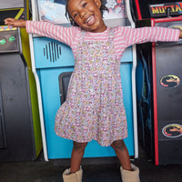 Little girl seen wearing our Essential Tee in Blush Stripe layered underneath our Beatrice Pinafore dress in Radnor Rose--BISBY girl