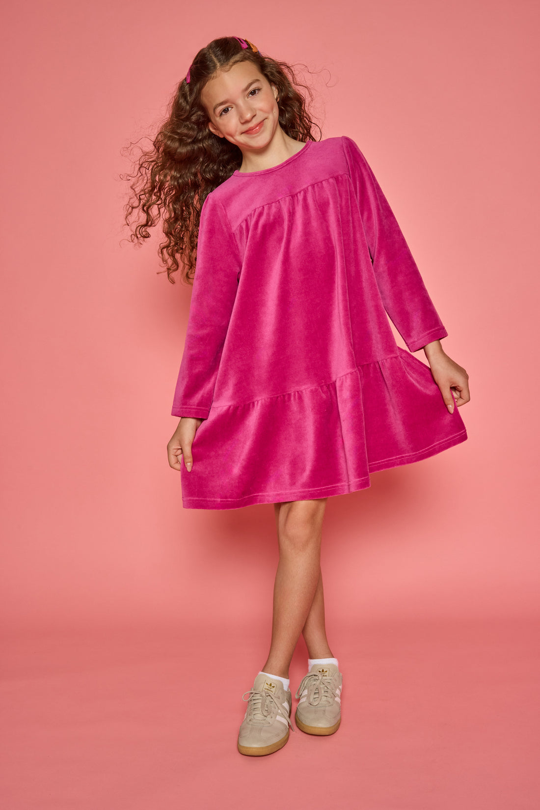 Model can be seen wearing a long sleeve magenta velour dress. Dress features button closure at back for a relaxed but secure fit. 