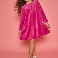 Model can be seen wearing a long sleeve magenta velour dress. Dress features button closure at back for a relaxed but secure fit. 