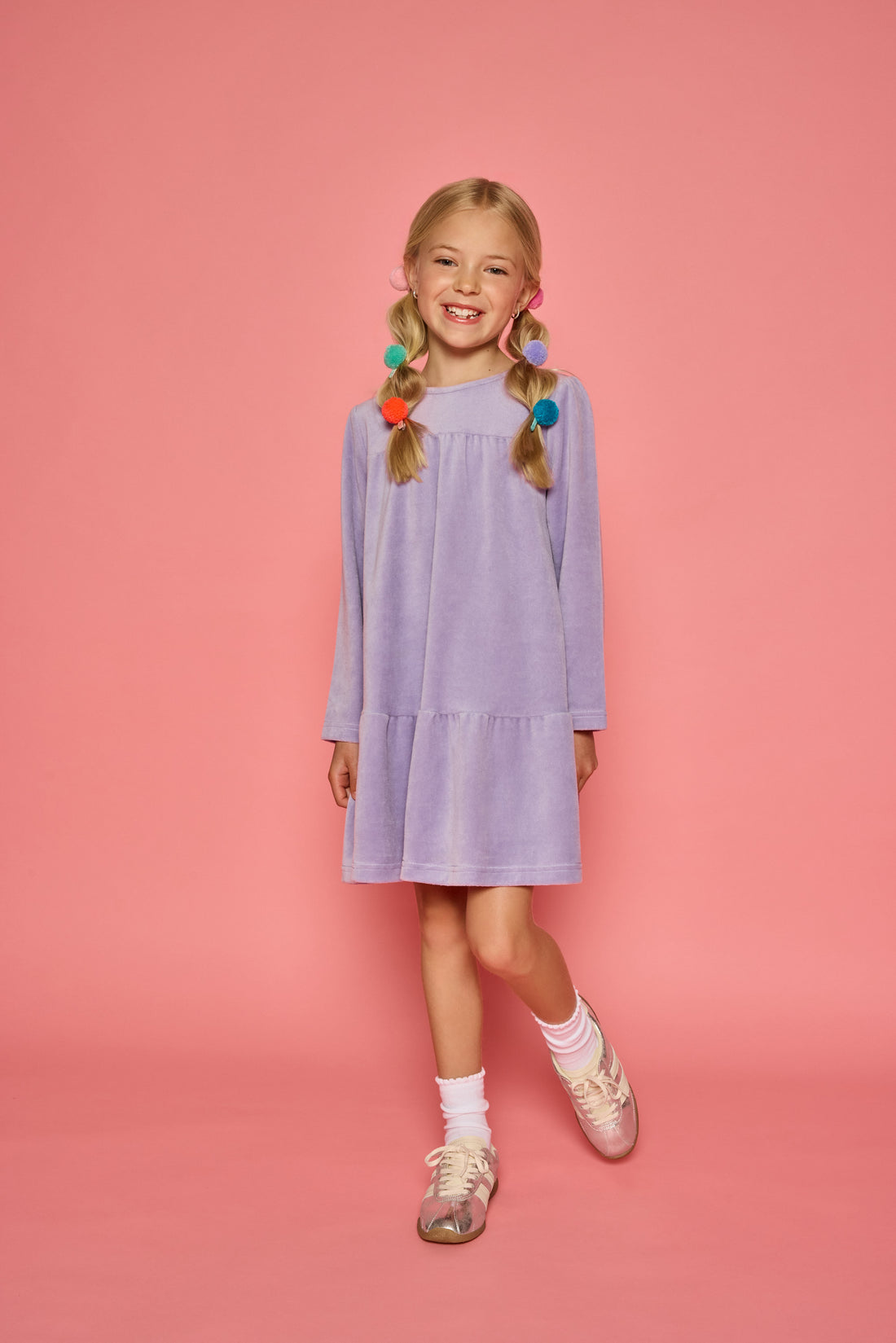 Model can be seen wearing a long sleeve lilac velour dress. Dress features button closure at back for a relaxed but secure fit. 