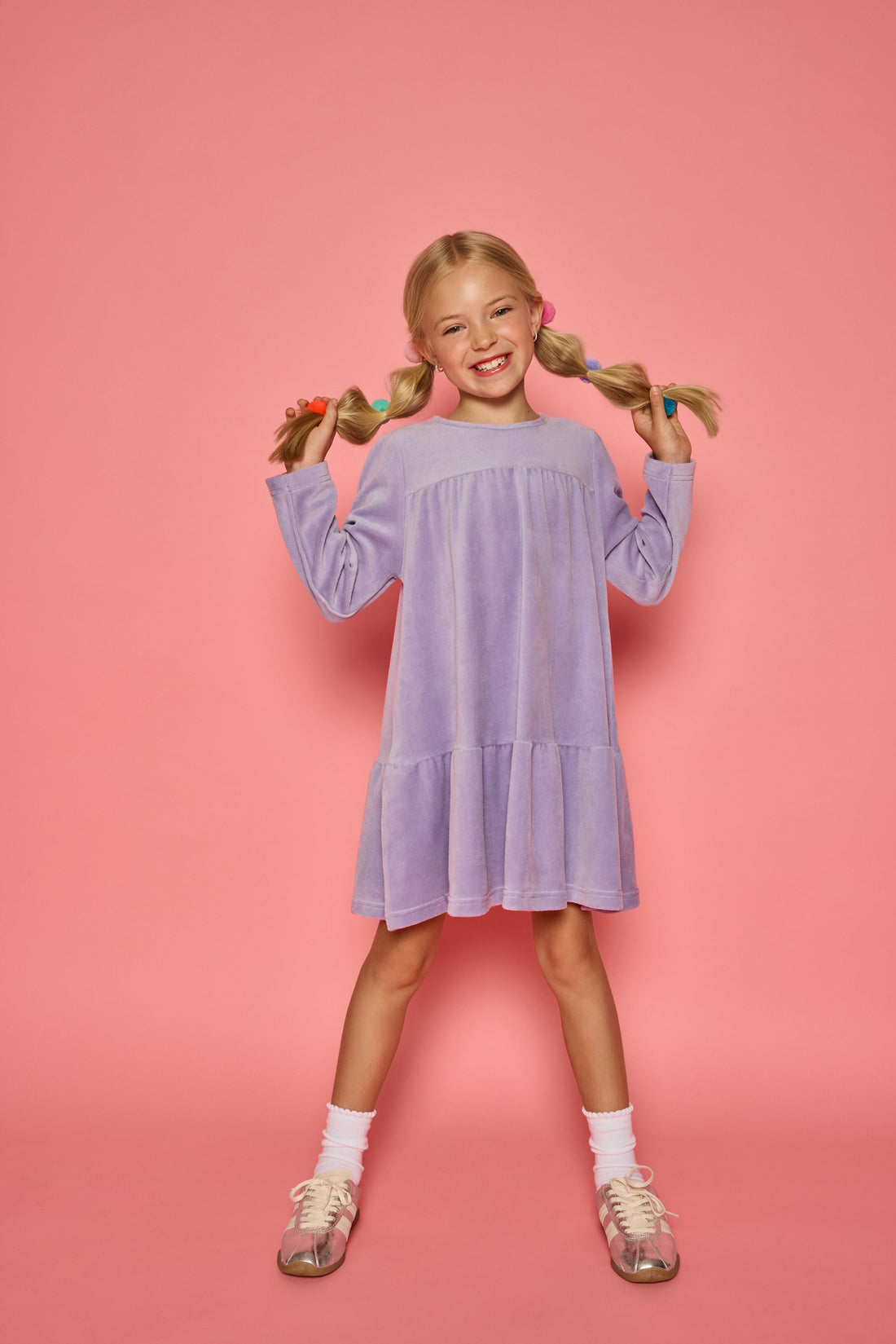 Model can be seen wearing a long sleeve lilac velour dress. Dress features button closure at back for a relaxed but secure fit. 