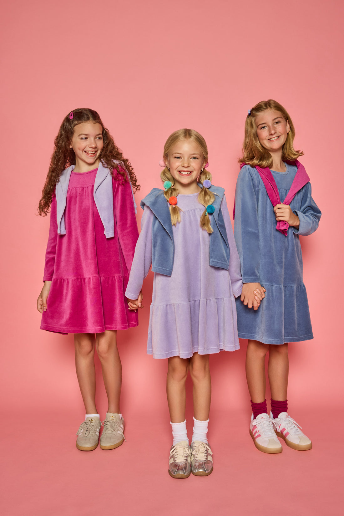 Models can be seen wearing long sleeve dusty blue/magenta/ and lilac velour dresses. Dresses features button closure at back for a relaxed but secure fit. 