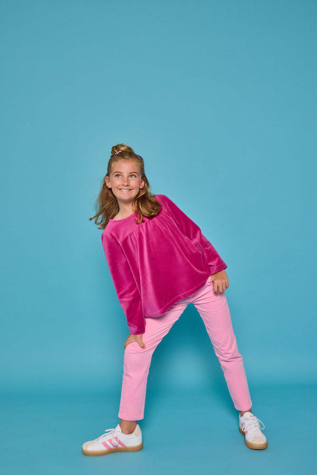 Model can be seen wearing long sleeve velour magenta top paired back with a pair of bubblegum pink corduroy pants. Top features button closure at back ad pants have pockets as well. 