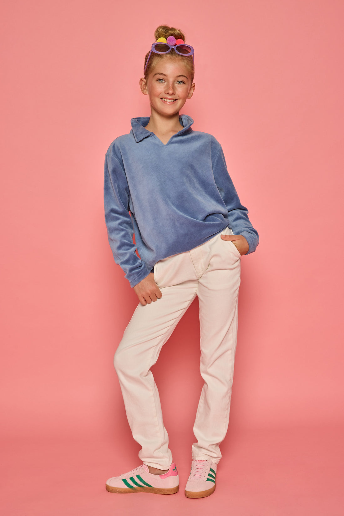 Model can be seen wearing a dusty blue velour pullover that features a fold over collar for easy over the head access. Paired back with basic white denim jeans to complete the look. 