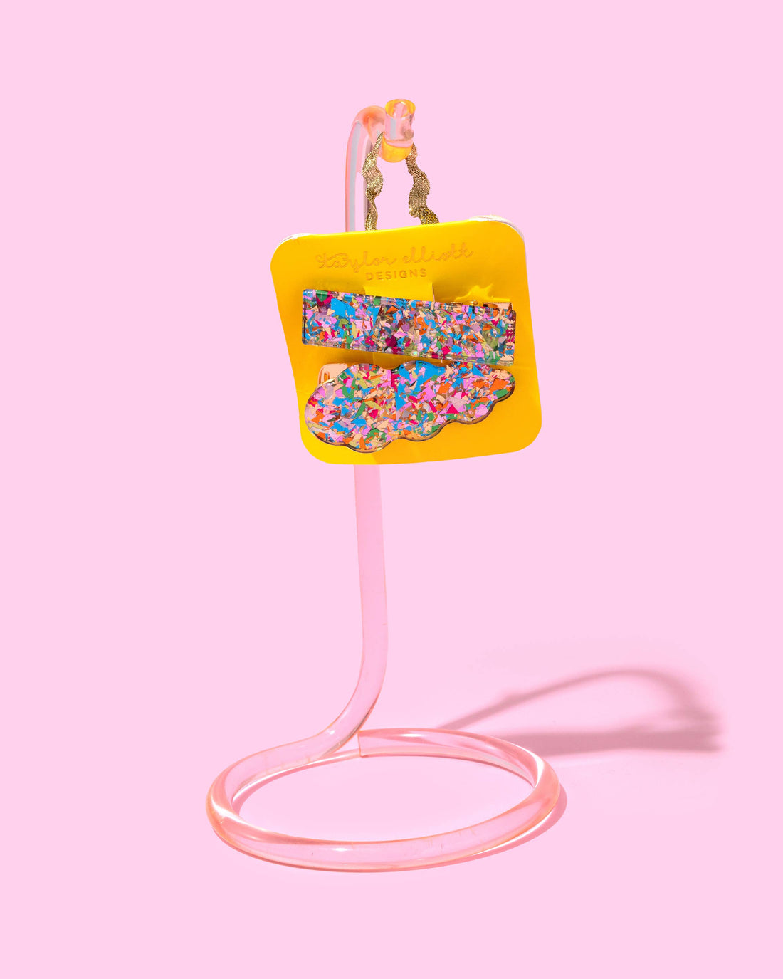 Colorful confetti hair clips on a yellow card.