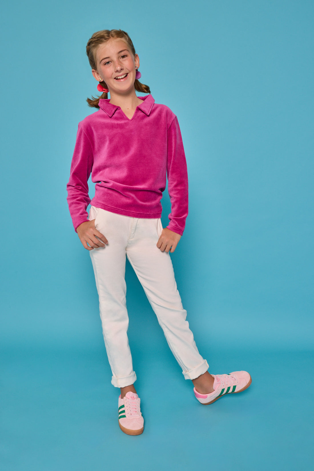Model can be seen wearing a magenta velour pullover that features a fold over collar for easy over the head access. Paired back with basic white denim jeans to complete the look. 