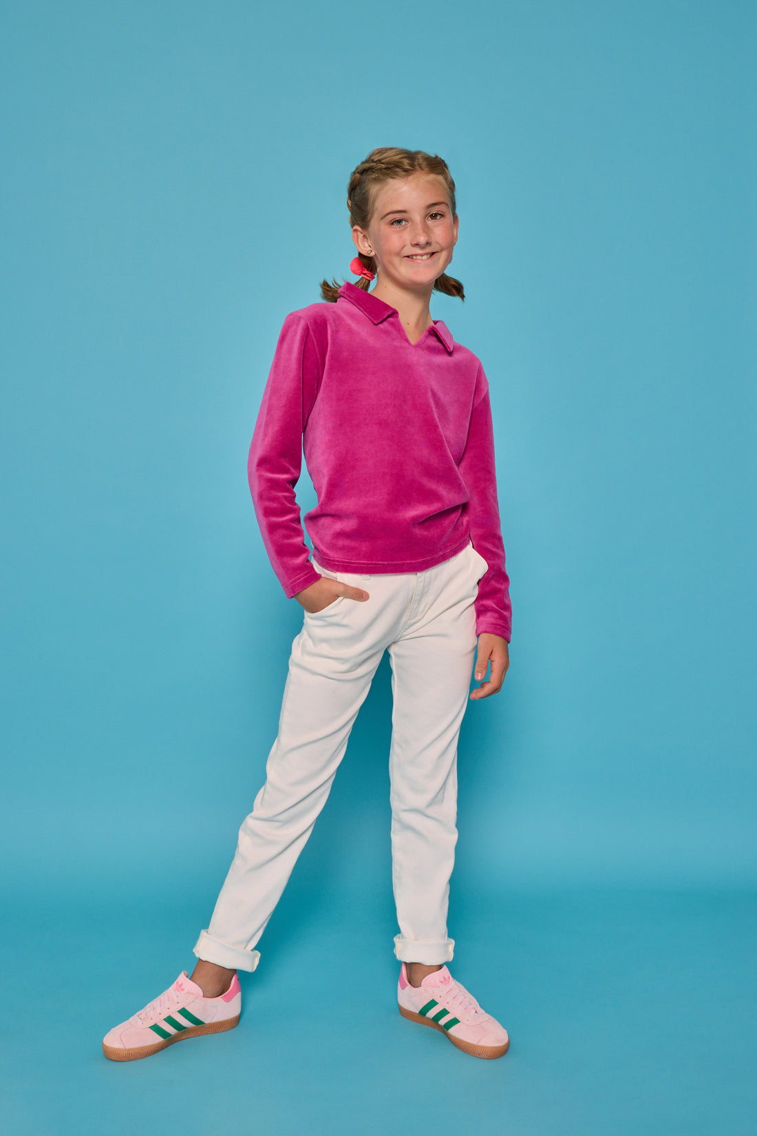 Model can be seen wearing a magenta velour pullover that features a fold over collar for easy over the head access. Paired back with basic white denim jeans to complete the look. 