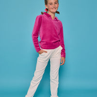 Model can be seen wearing a magenta velour pullover that features a fold over collar for easy over the head access. Paired back with basic white denim jeans to complete the look. 