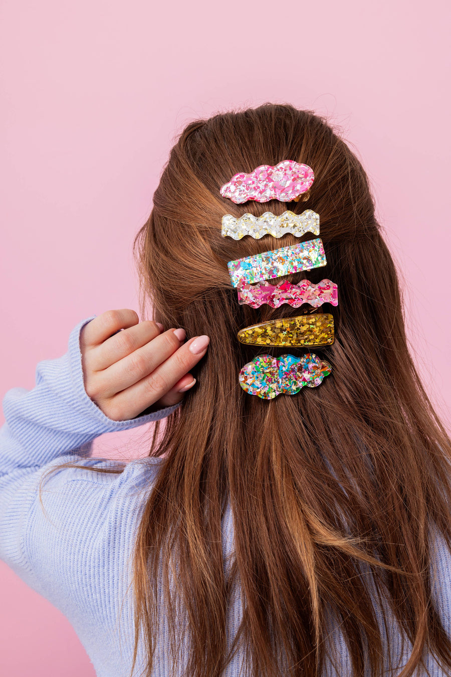 Person with colorful hair clips against a pink background