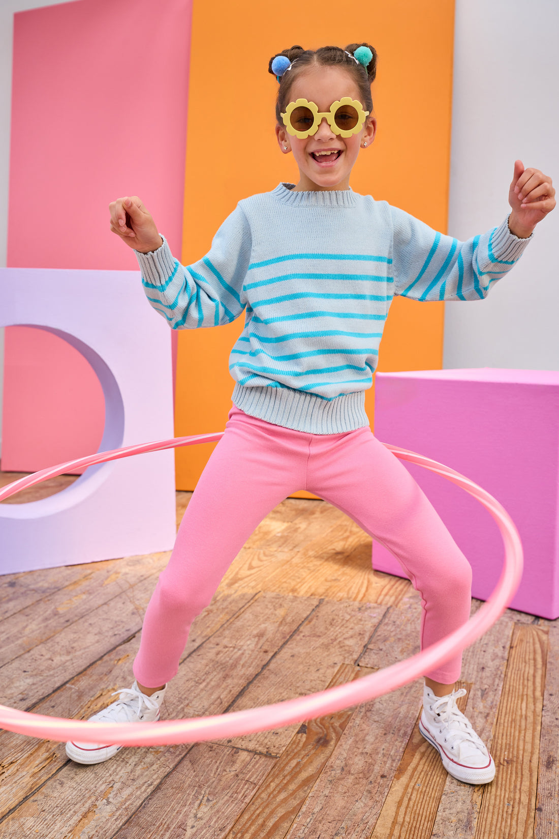 Tween model can be seen wearing an aqua stripe sweater paired back with leggings in a hot pink color to complete the vibrant look.