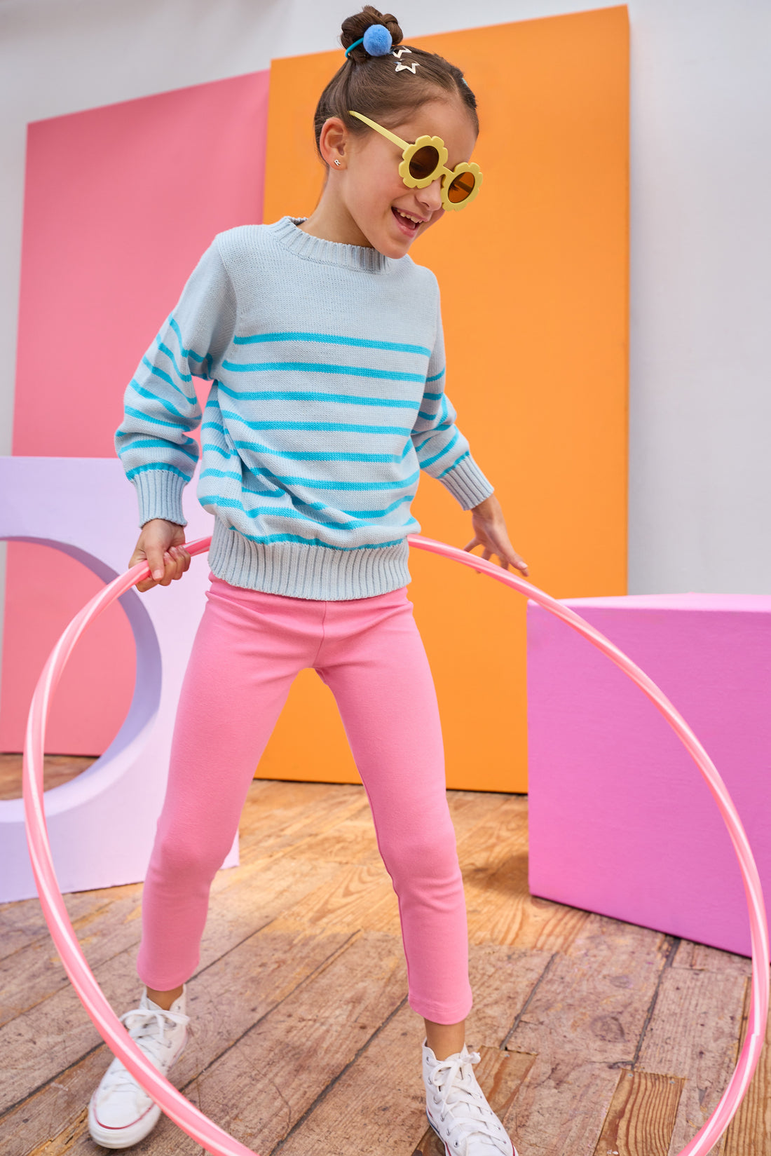 Tween model can be seen wearing an aqua stripe sweater paired back with leggings in a hot pink color to complete the vibrant look.